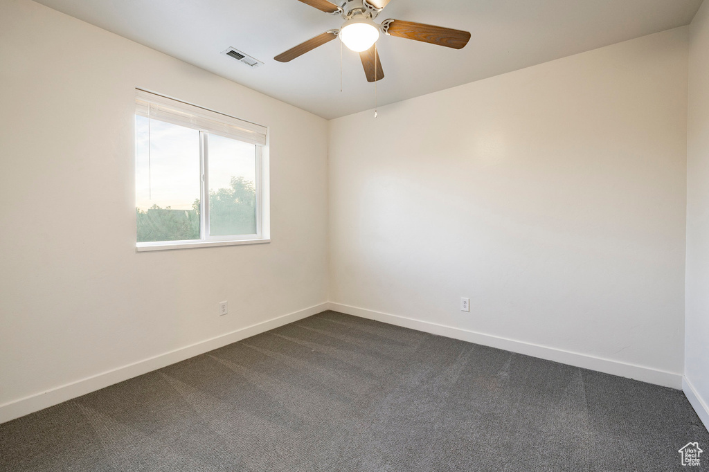 Empty room with baseboards, ceiling fan, and dark colored carpet