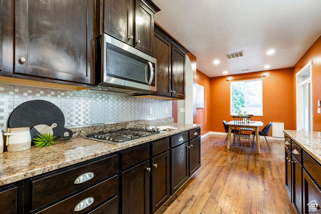 Kitchen featuring stainless steel appliances, light wood-style flooring, dark brown cabinetry, tasteful backsplash, and recessed lighting