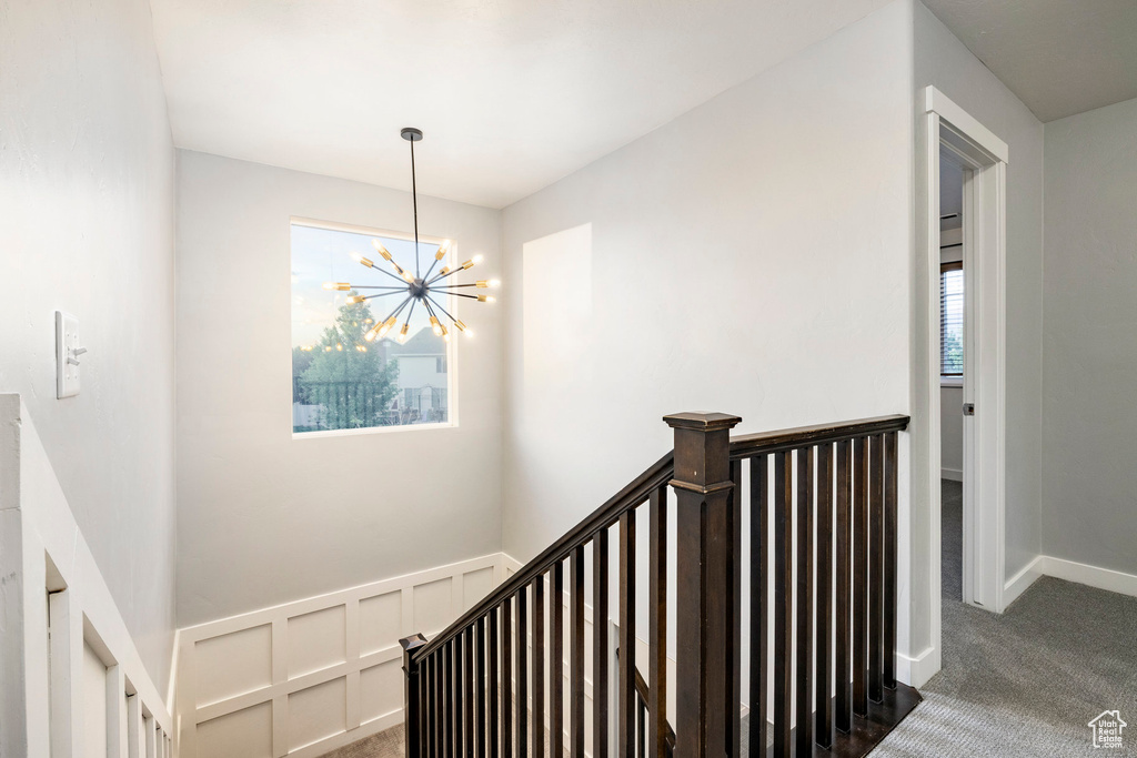 Staircase with a chandelier, carpet flooring, and baseboards