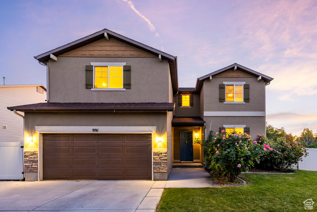 View of front of property with stucco siding, driveway, a garage, and stone siding