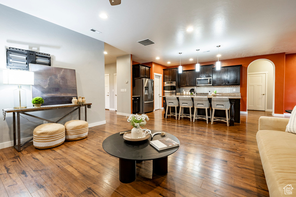 Living area with arched walkways, baseboards, dark wood-style floors, and recessed lighting