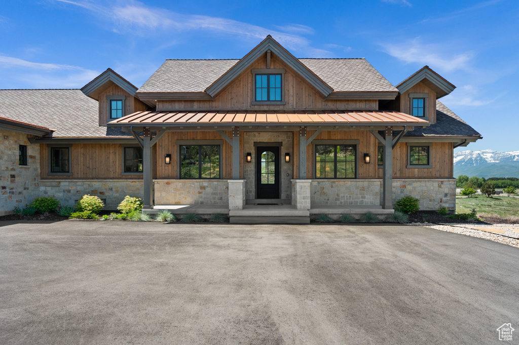 View of front of home with a porch, stone siding, a standing seam roof, and a shingled roof