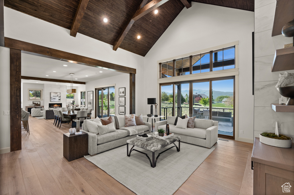 Living area featuring light wood-type flooring, high vaulted ceiling, a mountain view, wooden ceiling with exposed beams, and recessed lighting