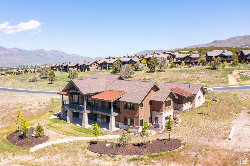 Rear view of house with a balcony, stone siding, a mountain view, and a residential view