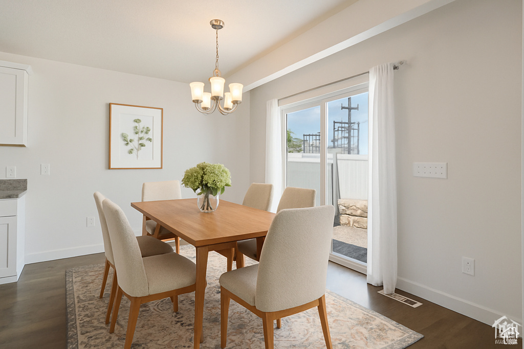 Dining room with a chandelier and dark wood-type flooring