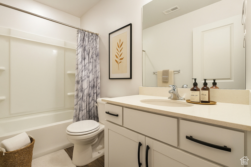 Full bath featuring vanity, shower / tub combo, and wood finished floors