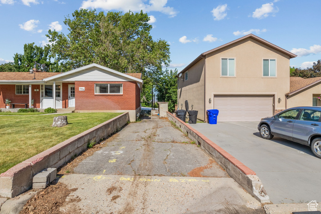 View of home's exterior featuring concrete driveway, a garage, brick siding, and a yard