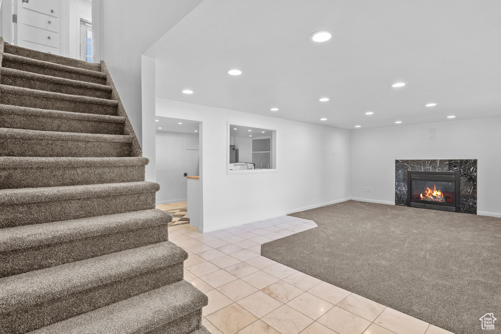 Below grade area with stairway, recessed lighting, a premium fireplace, carpet flooring, and baseboards