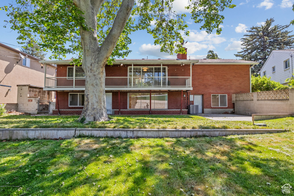 Back of property featuring brick siding, a patio, a chimney, and central AC