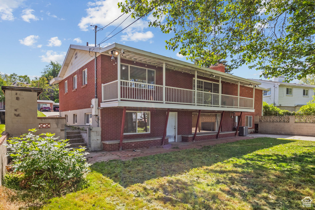 Back of property featuring brick siding, a chimney, and central AC