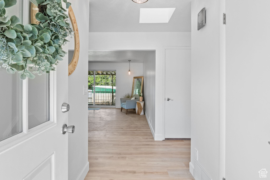 Foyer featuring a skylight, light wood-style floors, and baseboards
