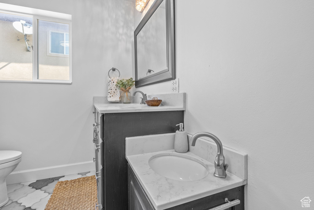 Bathroom featuring vanity, toilet, marble finish flooring, and baseboards