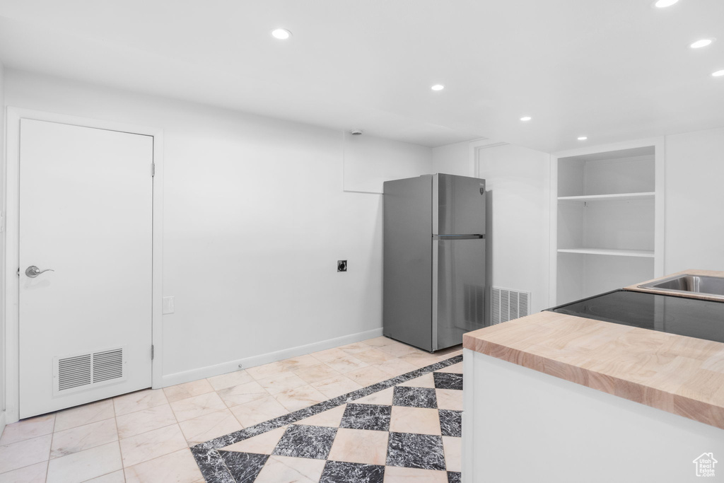 Kitchen with freestanding refrigerator, recessed lighting, butcher block counters, electric range oven, and a sink