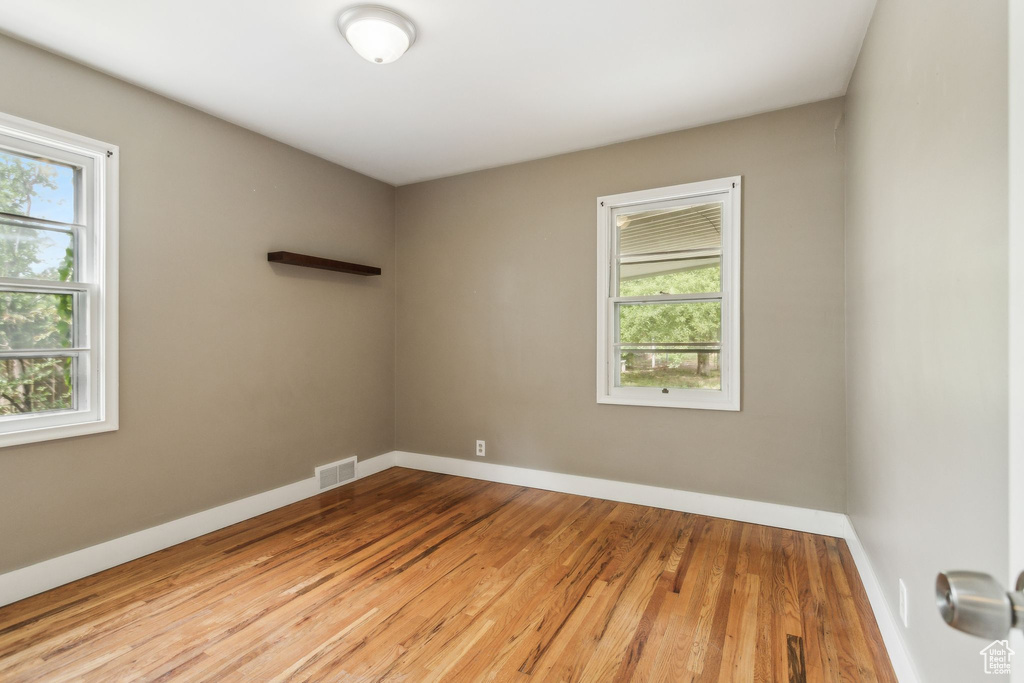 Spare room with healthy amount of natural light, wood finished floors, and baseboards