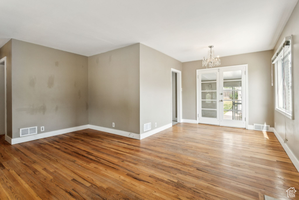 Unfurnished room featuring wood finished floors, a chandelier, and baseboards
