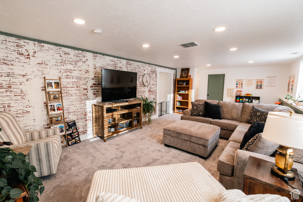 Living room featuring light carpet, recessed lighting, and brick wall