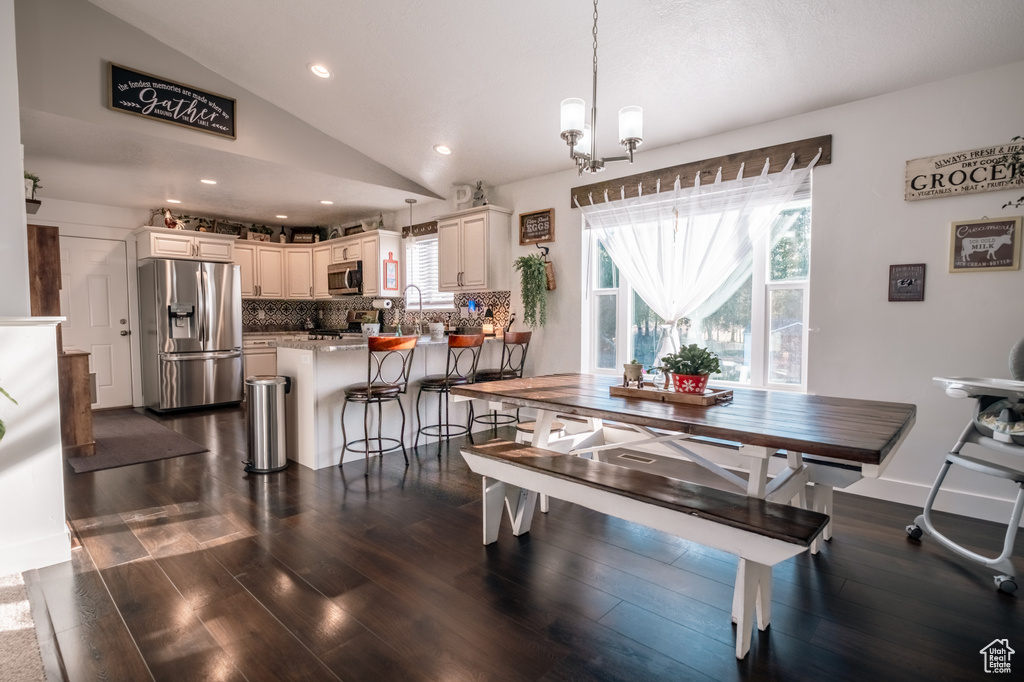 Dining area with vaulted ceiling, dark wood-style floors, recessed lighting, and a chandelier