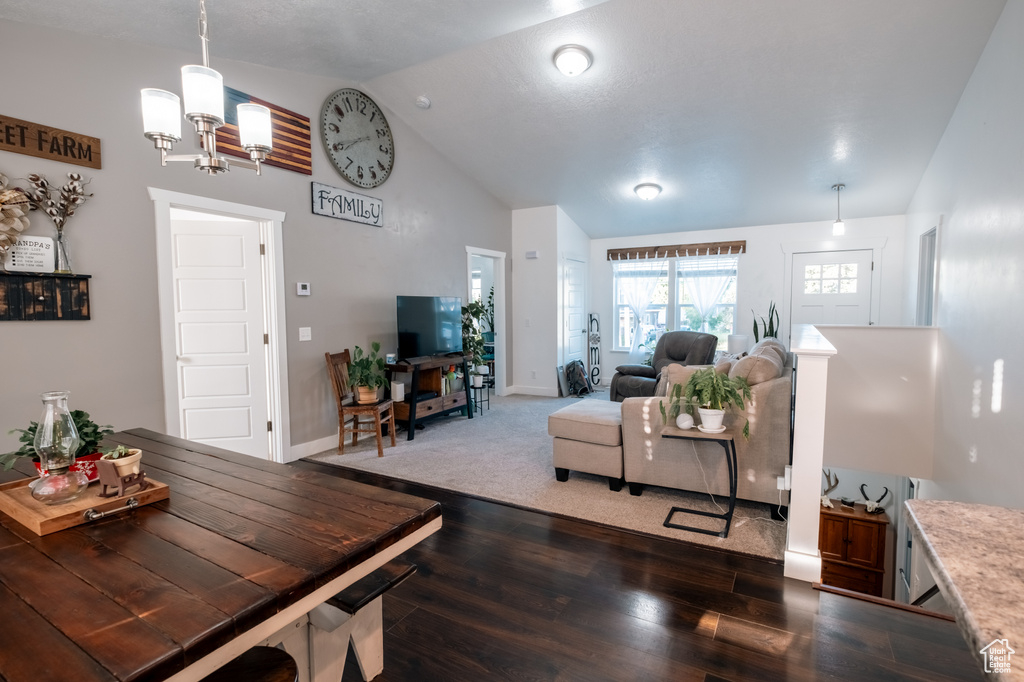 Living area with dark wood-style flooring, a chandelier, high vaulted ceiling, and baseboards