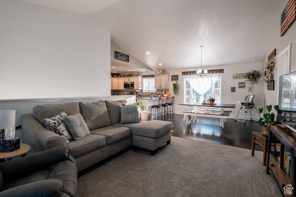 Carpeted living room with a chandelier, vaulted ceiling, wood finished floors, and recessed lighting