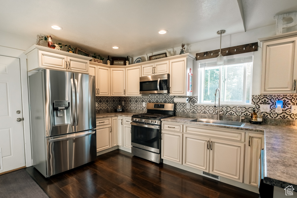 Kitchen with appliances with stainless steel finishes, a sink, dark wood finished floors, backsplash, and recessed lighting