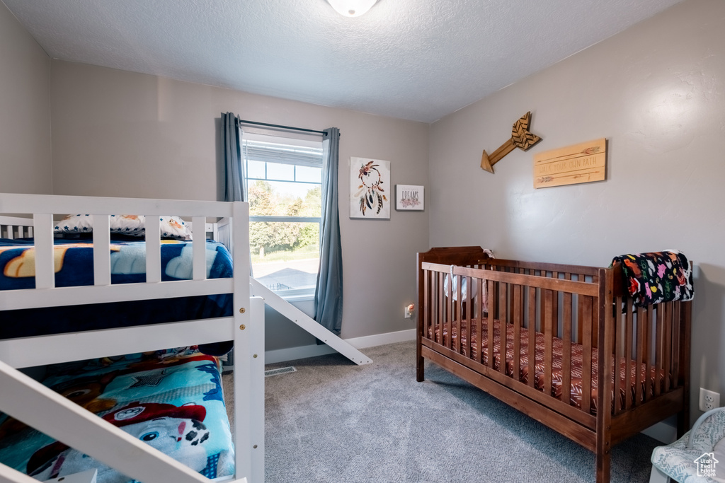 Bedroom with carpet, a textured ceiling, and baseboards