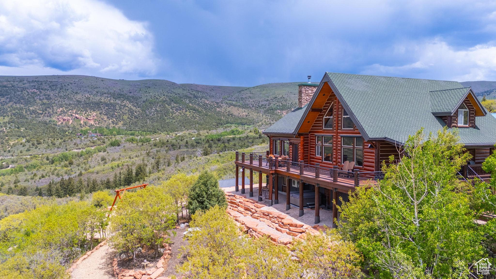 Rear view of house with a deck with mountain view, a chimney, and log exterior