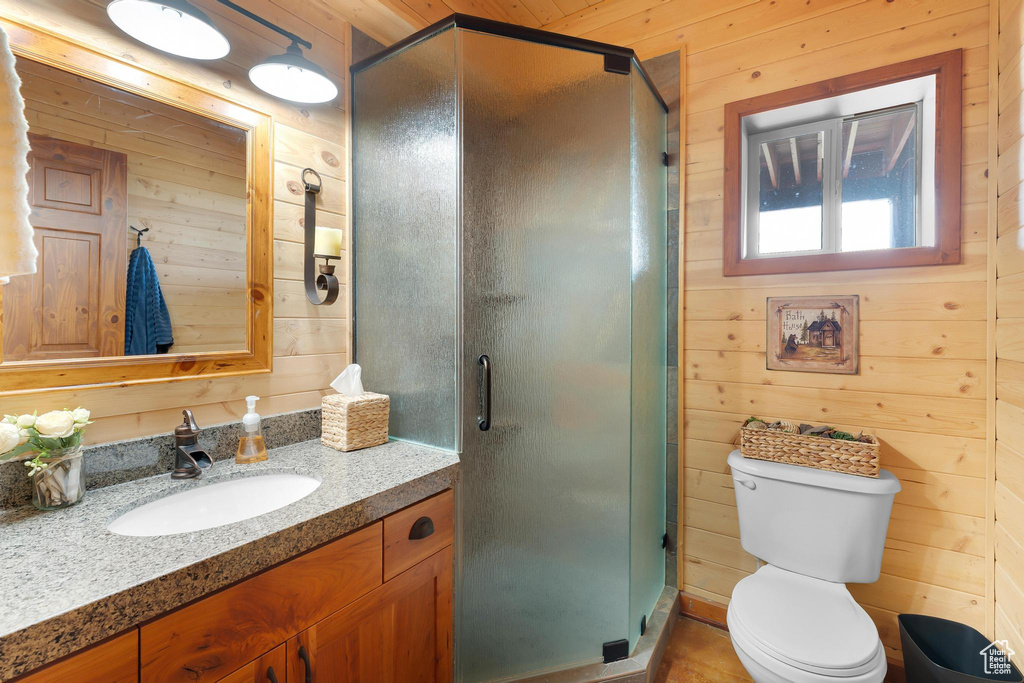 Bathroom featuring wood walls, vanity, a stall shower, and toilet