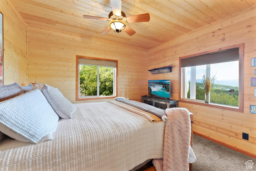 Bedroom with carpet flooring, wood walls, wood ceiling, and ceiling fan