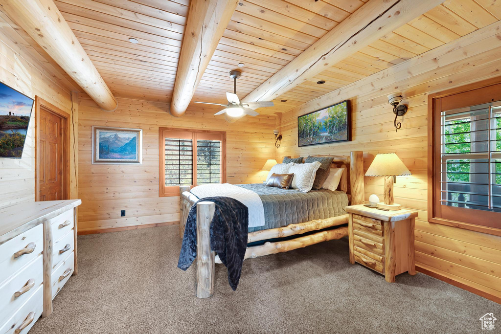 Bedroom featuring multiple windows, wood ceiling with exposed beams, wood walls, light carpet, and a ceiling fan