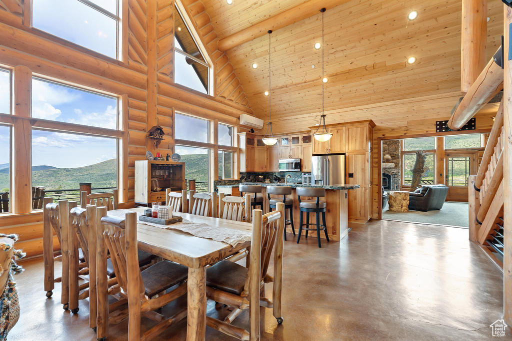 Dining room with high vaulted ceiling, wooden ceiling, recessed lighting, concrete flooring, and log walls
