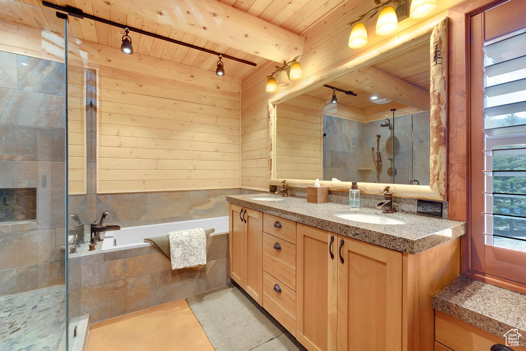 Bathroom featuring wooden ceiling with exposed beams, double vanity, a garden tub, a shower stall, and rail lighting