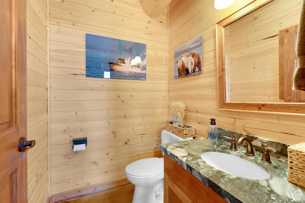 Bathroom featuring vanity, wood walls, and toilet
