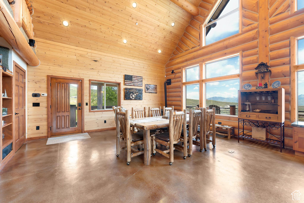 Dining room with high vaulted ceiling, finished concrete floors, recessed lighting, healthy amount of natural light, and wood ceiling