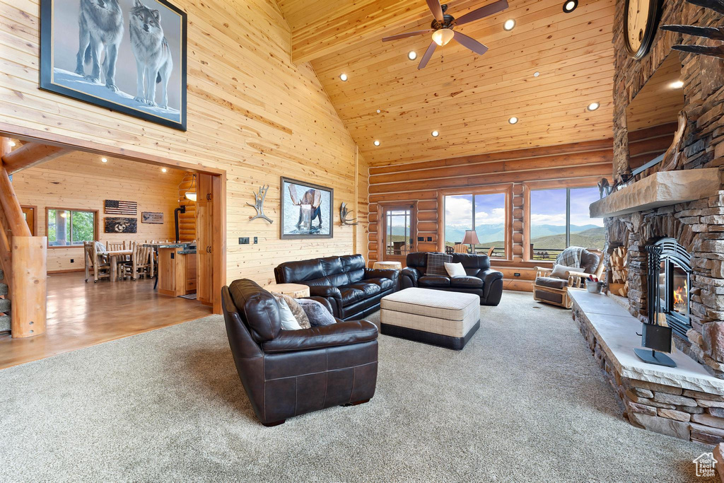 Living area with high vaulted ceiling, ceiling fan, carpet floors, a stone fireplace, and recessed lighting