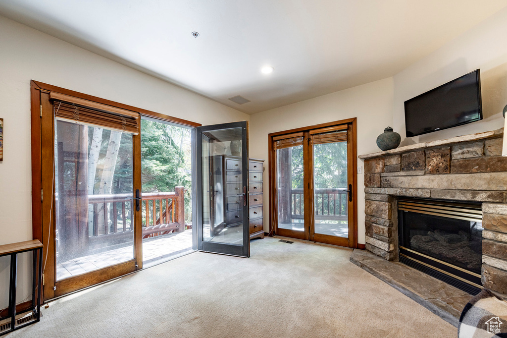 Unfurnished living room featuring carpet, plenty of natural light, a stone fireplace, and recessed lighting