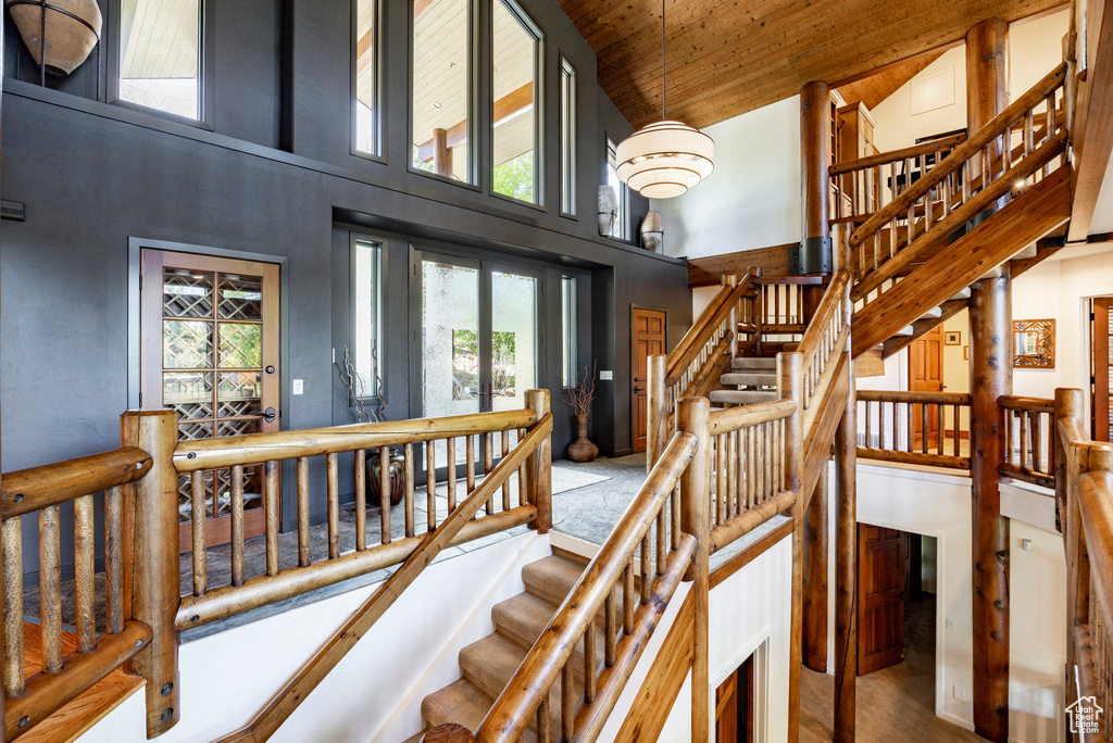 Stairs with high vaulted ceiling, plenty of natural light, and wooden ceiling