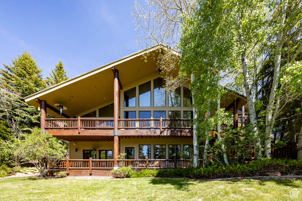 Back of property featuring a yard and a wooden deck