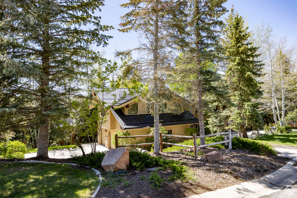 View of property exterior featuring a garage, metal roof, and stucco siding