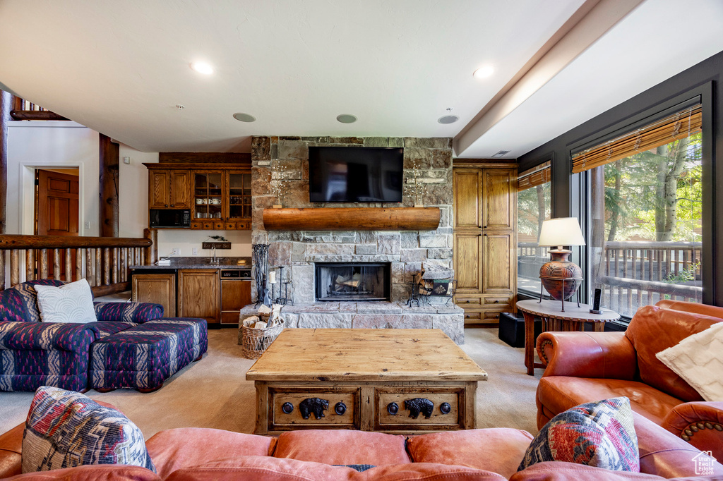 Living area with light colored carpet and a stone fireplace