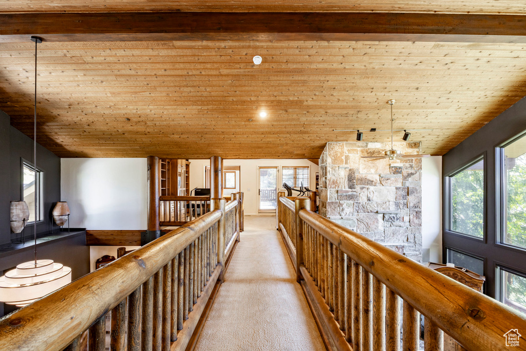 Corridor with wood ceiling, light colored carpet, healthy amount of natural light, and an upstairs landing