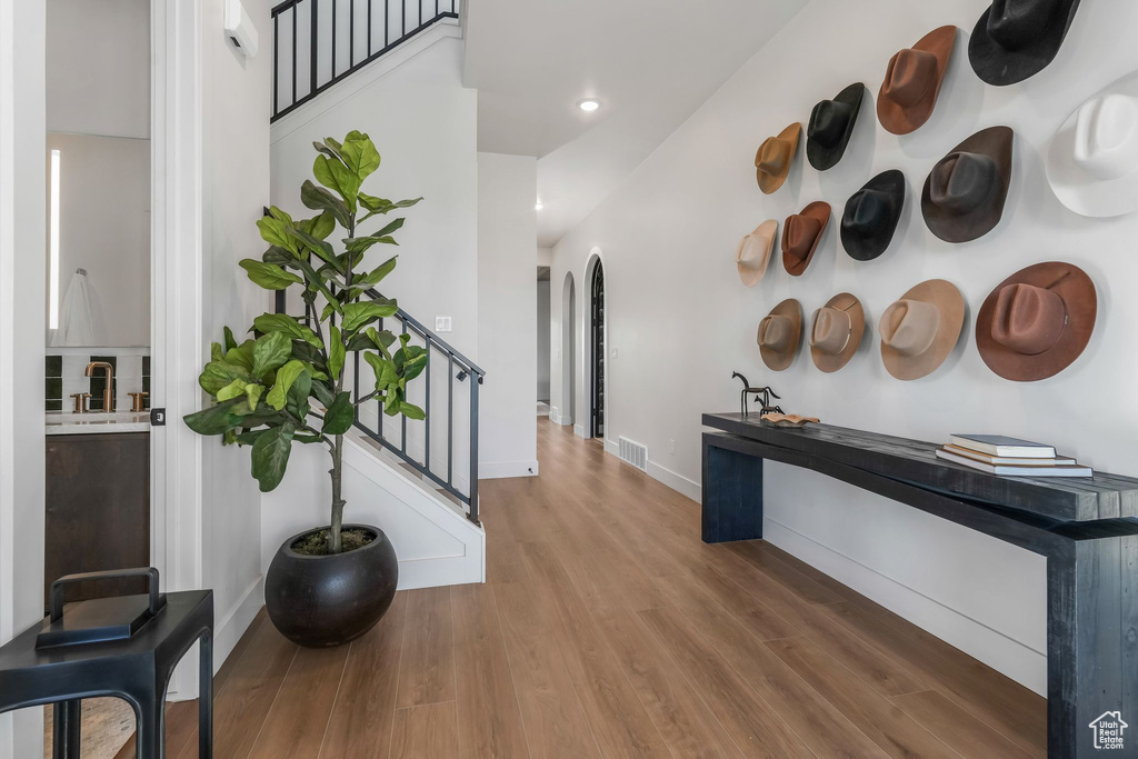 Hallway featuring wood finished floors, baseboards, stairway, arched walkways, and recessed lighting