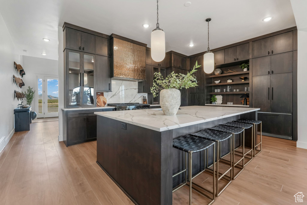 Kitchen with open shelves, a center island, dark brown cabinets, pendant lighting, and recessed lighting