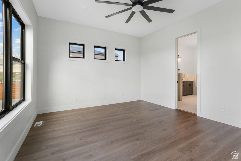 Unfurnished room featuring healthy amount of natural light, a ceiling fan, wood finished floors, and baseboards
