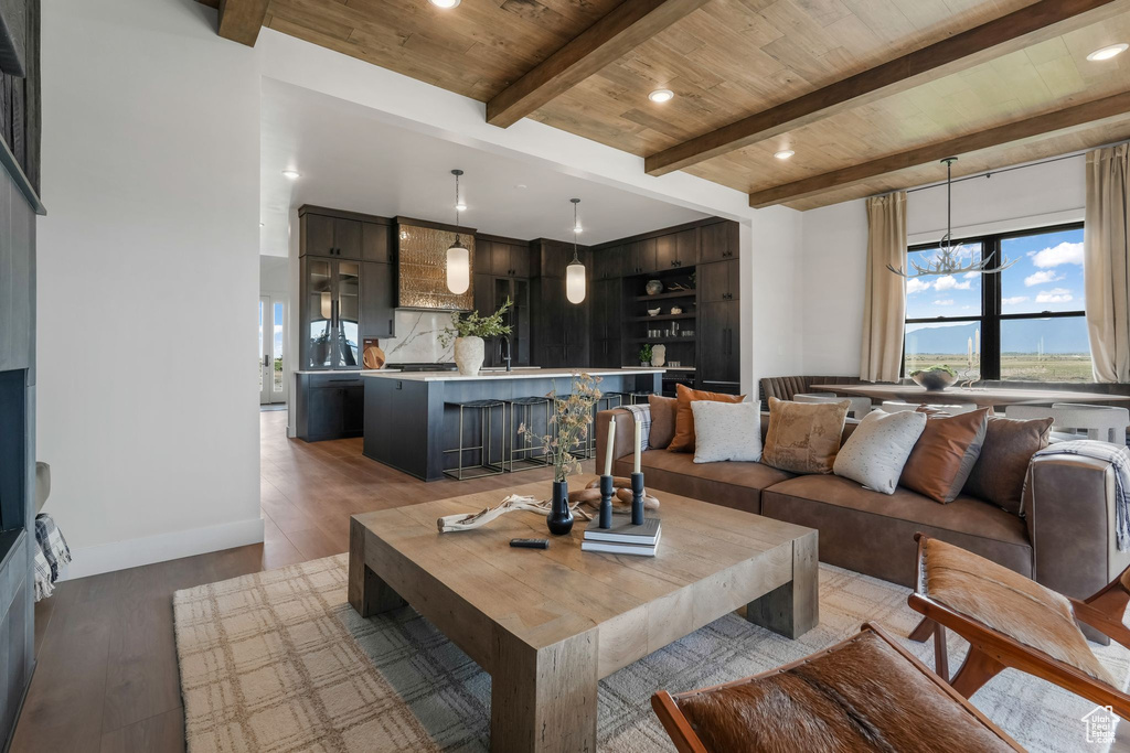 Living area with wooden ceiling with exposed beams, light wood-style floors, a chandelier, baseboards, and recessed lighting