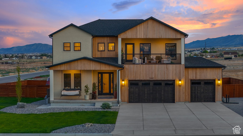 Modern home featuring a balcony, a mountain view, driveway, and covered porch