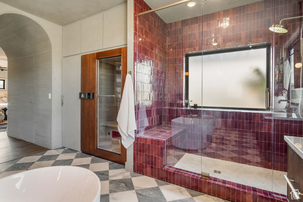 Full bathroom with tiled shower, a bathtub, and tile walls