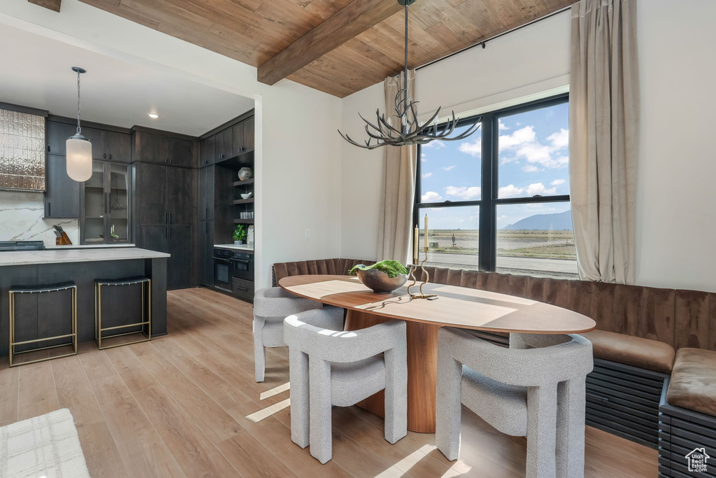 Dining room featuring light wood-style floors, a chandelier, and wooden ceiling with exposed beams