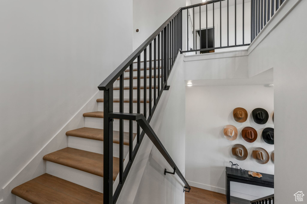 Stairs with a high ceiling, wood finished floors, and baseboards