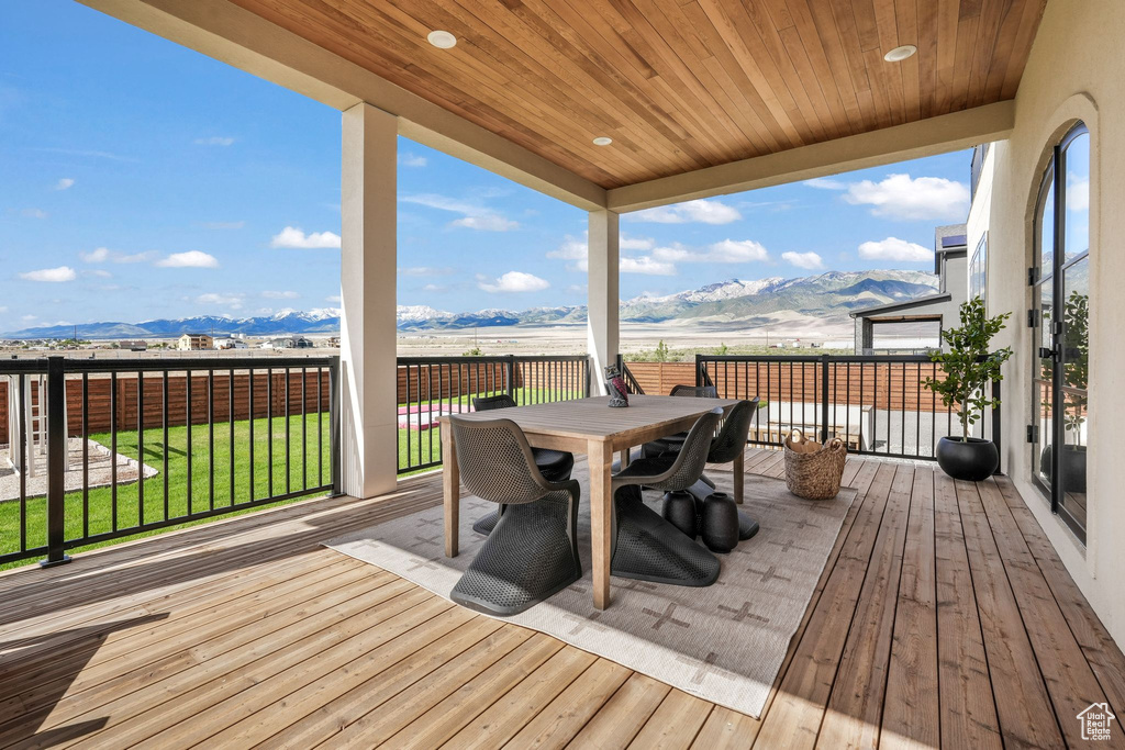 Wooden terrace with a mountain view, a lawn, and outdoor dining area