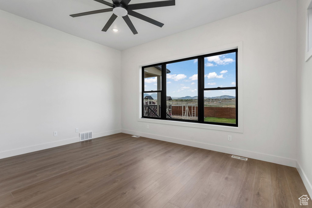 Spare room featuring ceiling fan, baseboards, and dark wood-style flooring
